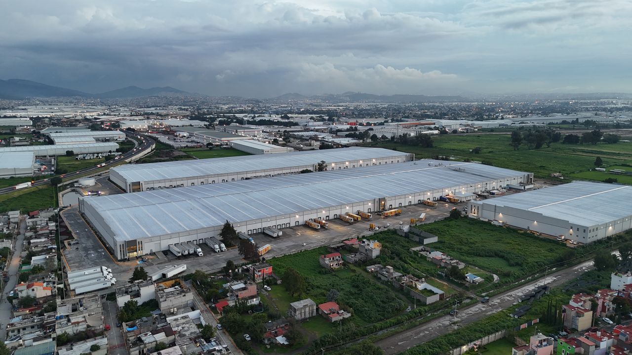 Aerial view of industrial warehouses in Mexico City surrounded by residential areas and greenery.