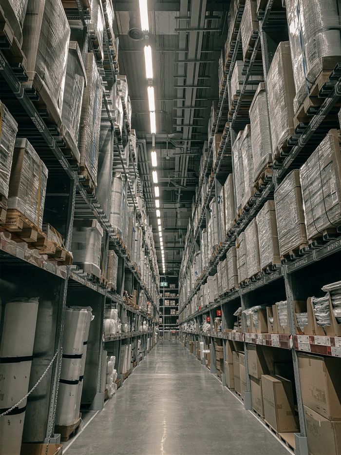 A long aisle in a modern warehouse with high shelving filled with boxes and supplies.