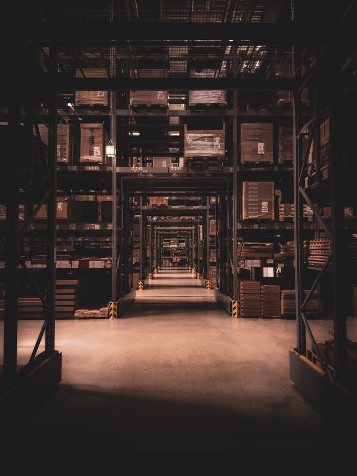 Dimly lit warehouse aisle in Berlin filled with large shelves and boxes, showcasing industrial organization.